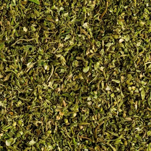 KARMA ORGANIC CBD TEA 4 Close-up of a pile of dried, chopped green herbs, featuring various shades of green and brown pieces. The texture is coarse and uneven, with small leaves and stems visible throughout—perfect for those seeking high-quality blends like KARMA ORGANIC CBD TEA in the UK.