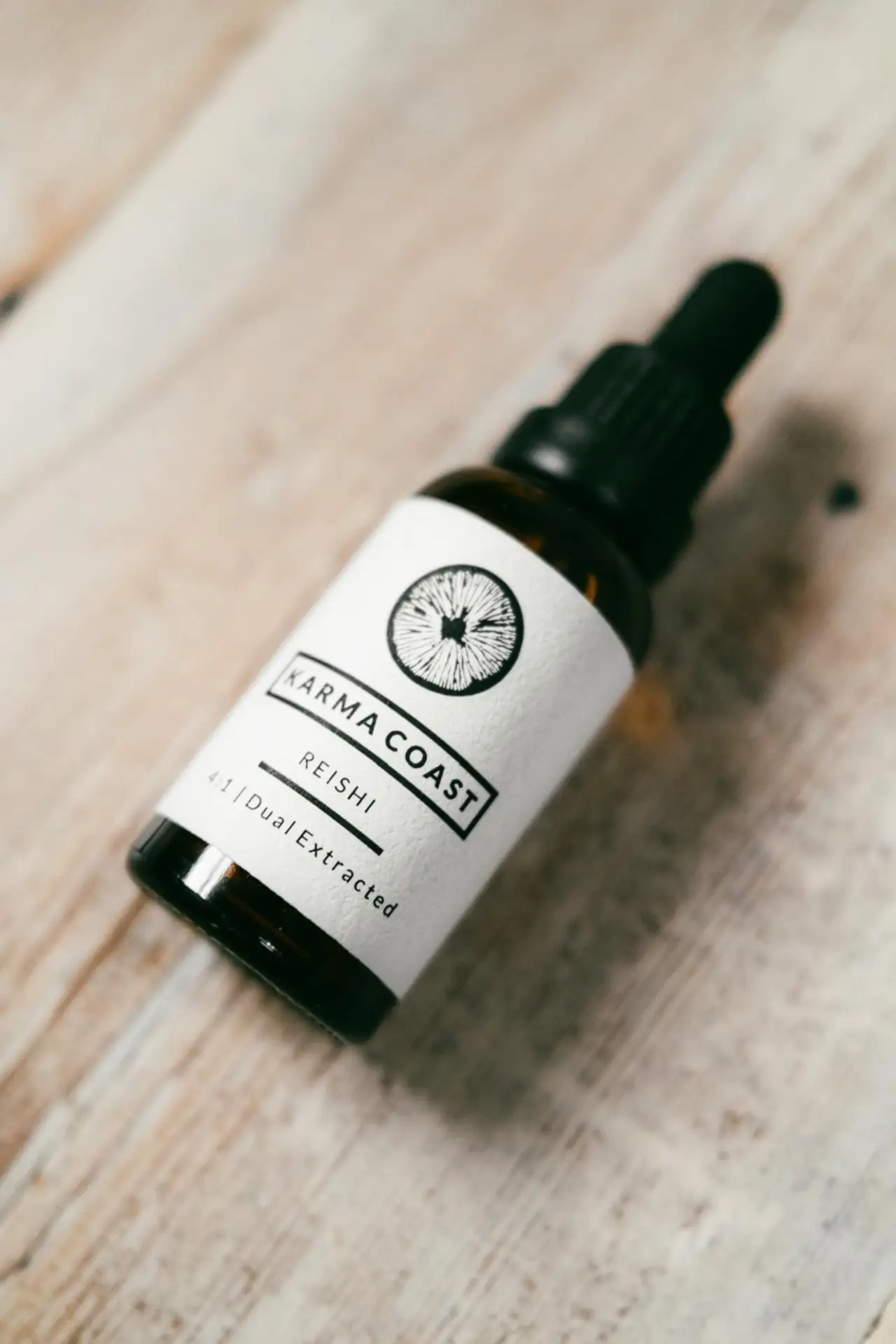 Reishi Dual Extract Tincture 2 A brown glass dropper bottle labelled Reishi Dual Extract Tincture sits on a light wooden surface.